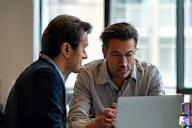 Two people discussing photos on a laptop